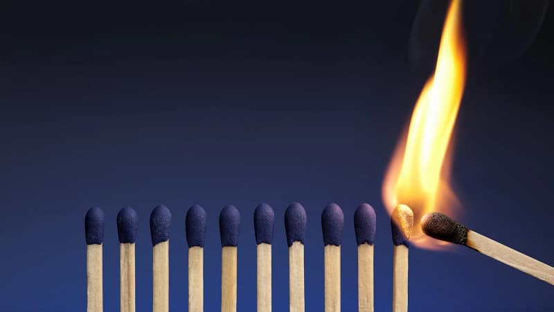 One lit match lighting a row of matches, representing a leader's influence spreading