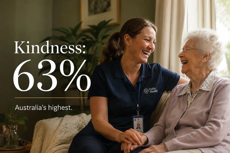 Aged care worker sharing a genuine laugh with an elderly resident in a bright Australian care home.